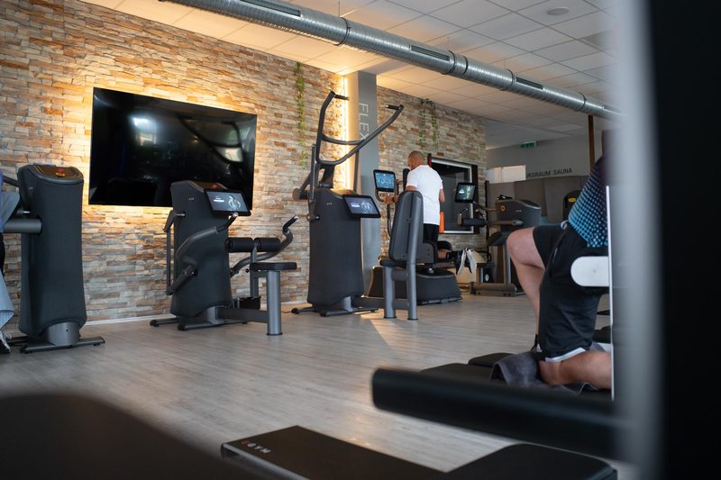 Trainingsbereich mit EGYM-Geräten vor Natursteinwand im Fit-Inn Heldenbergen