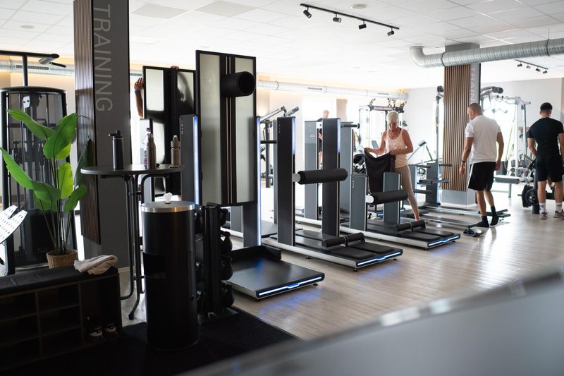 Trainingsfläche mit Kraftgeräten und trainierenden Mitgliedern im Fit-Inn Heldenbergen