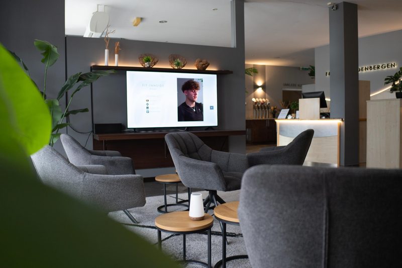Loungebereich mit Sesseln und Bildschirm im Fit-Inn Heldenbergen